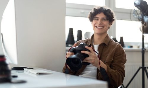 smiling-man-holding-camera-in-bright-workspace-2026-01-08-23-03-20-utc_optimized_200